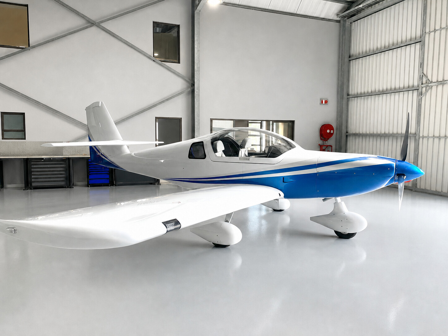 Side view of a completed blue and silver Whisper X350 in a freshly painted hangar